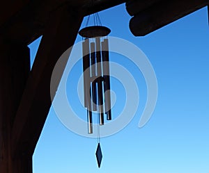 Silhouette of wind chimes against clear blue sky.