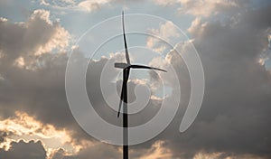 Silhouette of a wind turbine against a summer evening sky with c