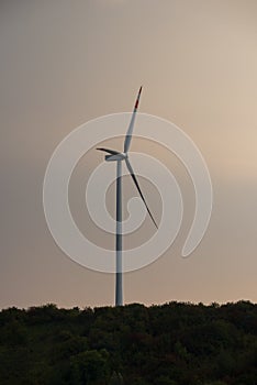 Silhouette of a wind turbine against a summer evening sky with c