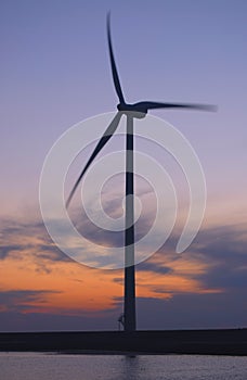 A silhouette of a wind turbine at dawn