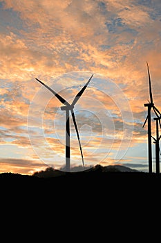 Silhouette of a wind turbine generating electricity on sky cloud background