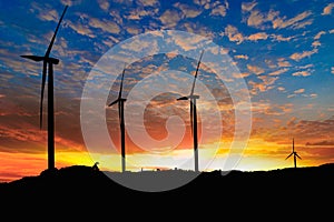 Silhouette of a wind turbine generating electricity on sky sunset background