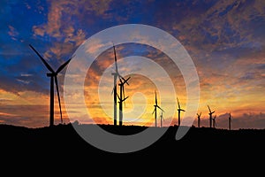 Silhouette of a wind turbine generating electricity on sky sunset background