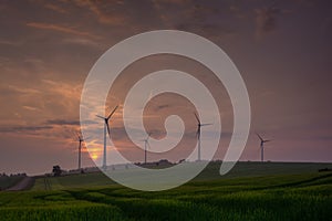 Silhouette of wind turbine generating electricity on sunset