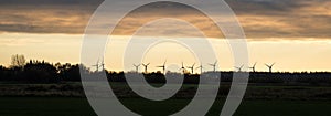 Silhouette of wind turbines or windmills creating electricity from wind power on field at sunset, Nordfriesland, Germany