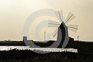 Silhouette of windmill used in salines during the sunset.