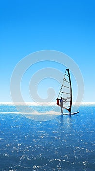 Silhouette of windsurfer gliding on calm blue ocean waters