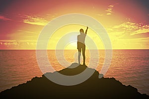 Silhouette of winning success woman at sunset or sunrise standing and raising up her hand in fighting concept