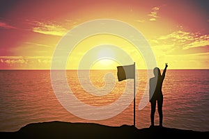 Silhouette of winning success woman at sunset or sunrise standing and raising up her hand near the flag in celebration