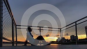 Silhouette of woman against sunset on a pier