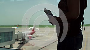 Silhouette of a woman in the airport terminal with a passport and boarding pass.