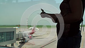 Silhouette of a woman in the airport terminal with a passport and boarding pass.