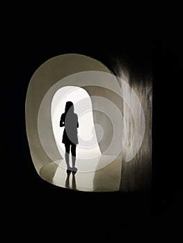 Silhouette of woman alone in front of light door, moving mental illness from the shadows into the light