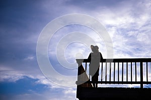 Silhouette of woman awesome shape in hat standing on balcony on