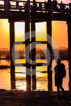 Silhouette of a woman with backpack at sunset under U bein bridge in Amarapura, Burma