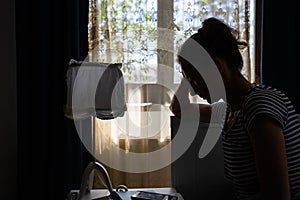 silhouette of woman by bedside holding her head mental health