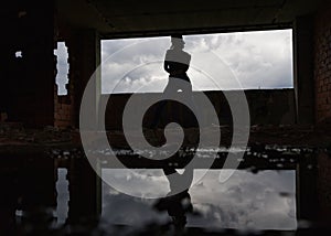 Silhouette of woman caucasian hip hop dancer, freestyling outdoors in an old abandoned building with refelection in puddle