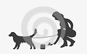 Silhouette of woman cleaning after a golden retriever dog.