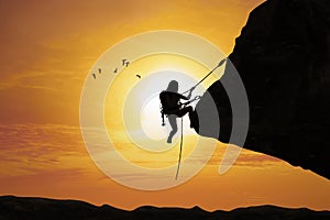 Silhouette of woman climbing on rock