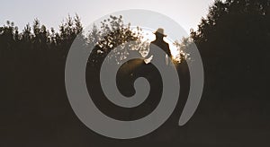 Silhouette of a woman in cowboy hat riding a horse - sunset