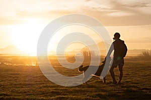 Silhouette of woman and dog walking on sunset background.