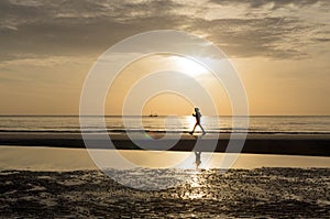Silhouette of woman doing a brisk walking on the beach at sunset