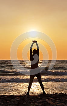 Silhouette of woman doing stretches on the beach