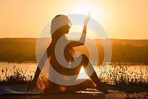 Silhouette of woman doing yoga against warm sun