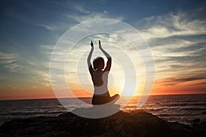 Silhouette of woman doing Yoga exercises on the sea beach