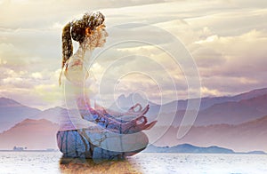 Silhouette of woman doing yoga in lotus position over lake landscape. Concept of connection with the universe and nature