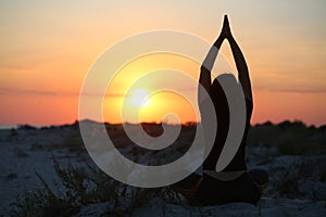 Silhouette of a woman doing yoga at the sunset sea shore