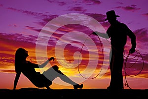 Silhouette woman in dress and heels look up at cowboy