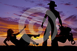 Silhouette woman in dress lay hand up cowboy with saddle