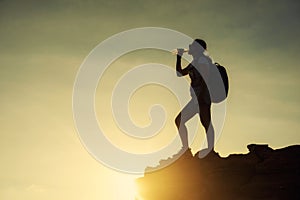 Silhouette woman drink water to cliff in sunset