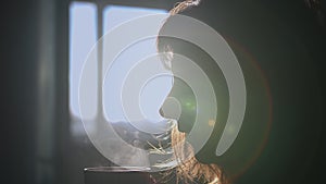Silhouette of a woman drinking hot coffee at home in the morning, steam in focus
