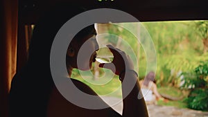 Silhouette of a woman drinking by the window, overlooking a lush garden