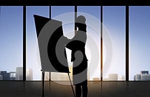 Silhouette of woman with flipboard over office