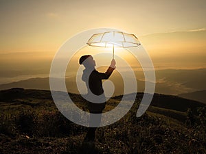 Silhouette woman hand holding umbrella on mountain at sunrise