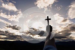 Silhouette of woman hands praying with cross  in nature sunrise background,  Crucifix, Symbol of Faith. Christian life crisis