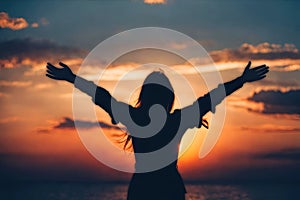 Silhouette of a woman happy and free open arms on beach.