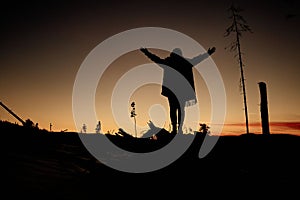 Silhouette of a woman with her arms spread wide during sunset/sunrise