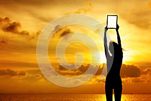 Silhouette of woman holding digital tablet