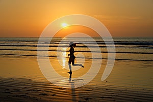 Silhouette of woman jogger running on sunset beach