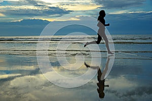 Silhouette of woman jogger running on sunset beach