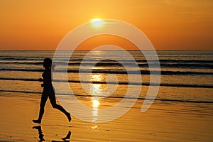 Silhouette of woman jogger running on sunset beach with reflection, fitness and sport