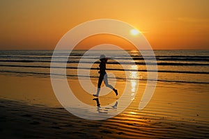 Silhouette of woman jogger running on sunset beach with reflection, fitness and sport