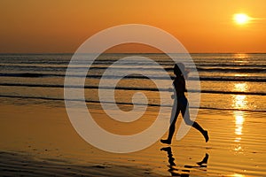 Silhouette of woman jogger running on sunset beach with reflection, fitness and sport