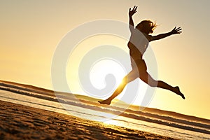 Silhouette, woman and jump at beach for sunset, happiness and celebration in nature for freedom. Energy, success and