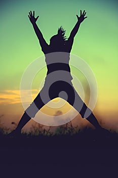 Silhouette of woman jumping against sunset. Young girl enjoying