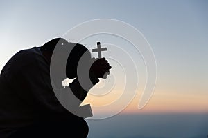 Silhouette of woman kneeling down praying for worship God at sky background. Christians pray to jesus christ for calmness. In